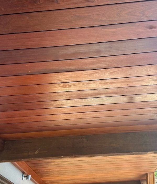 Warm-toned wooden ceiling with horizontal planks, supported by a dark beam. Soft natural light enhances the texture, creating a cozy, inviting atmosphere.
